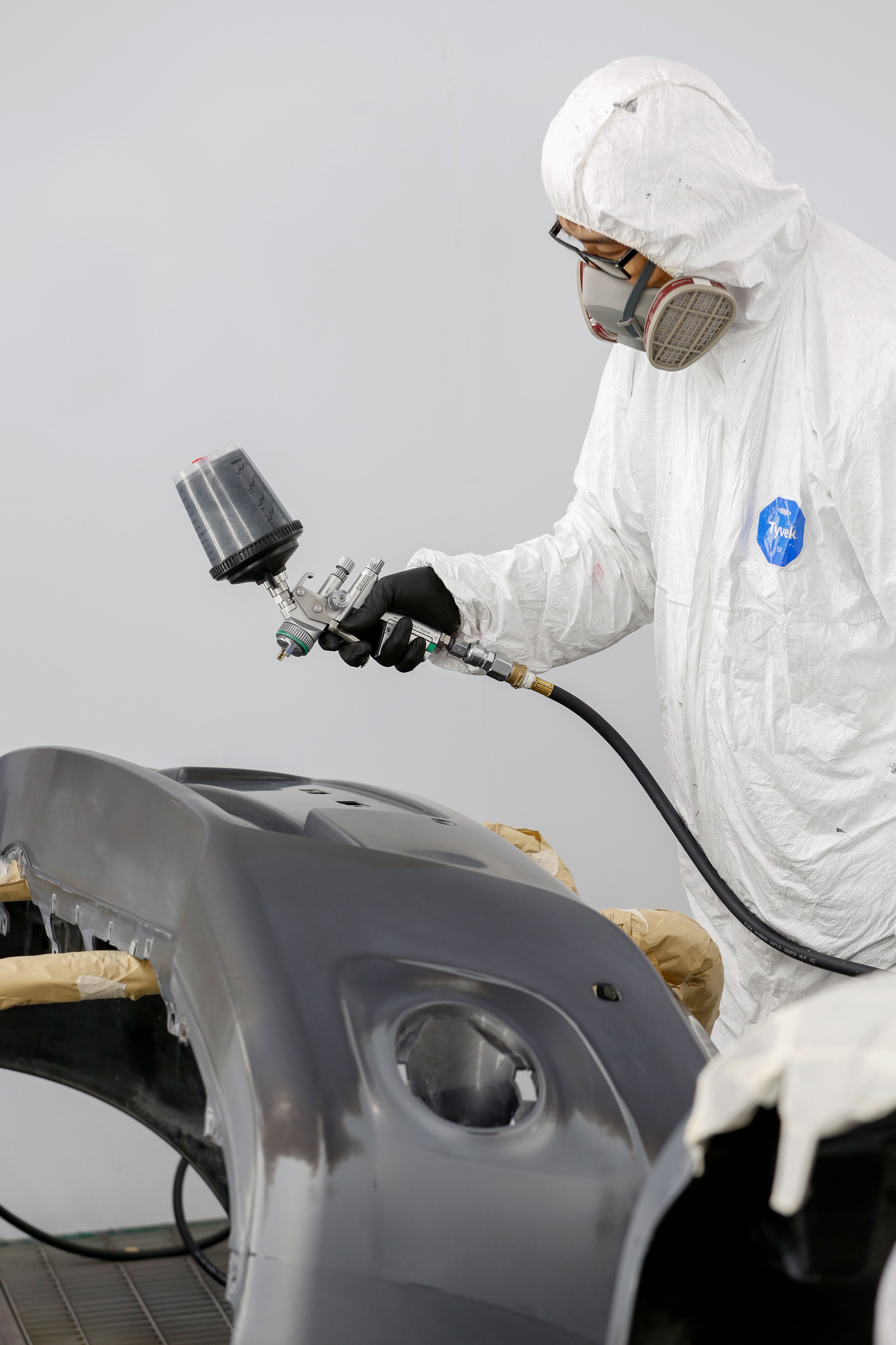 Auto body technician spray-painting a car in a workshop
